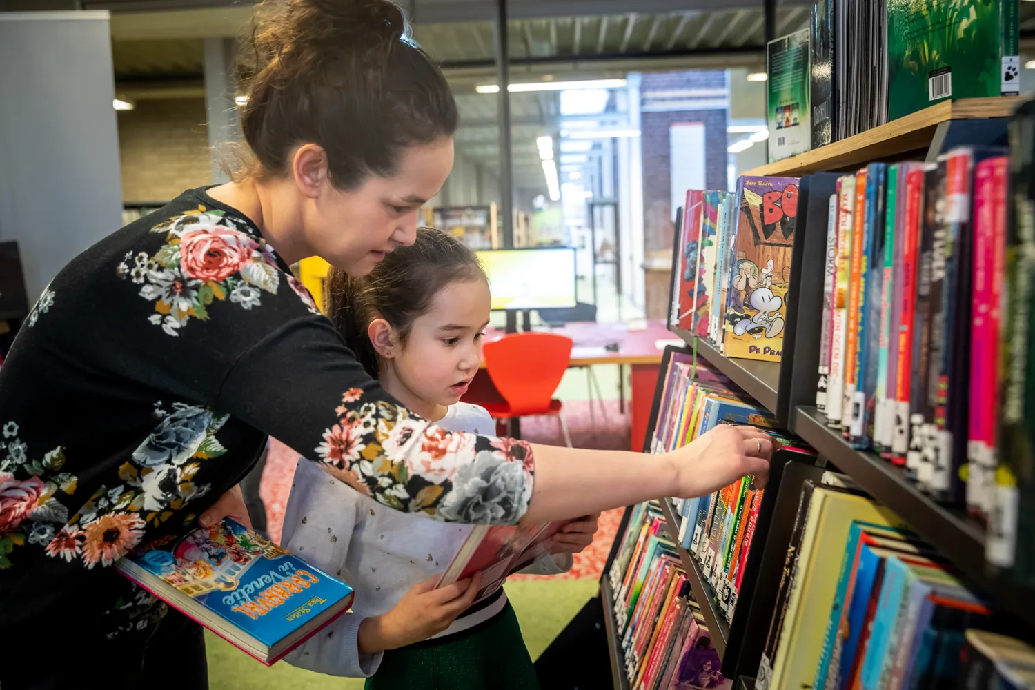 Moeder en kind zoeken boeken in kast 