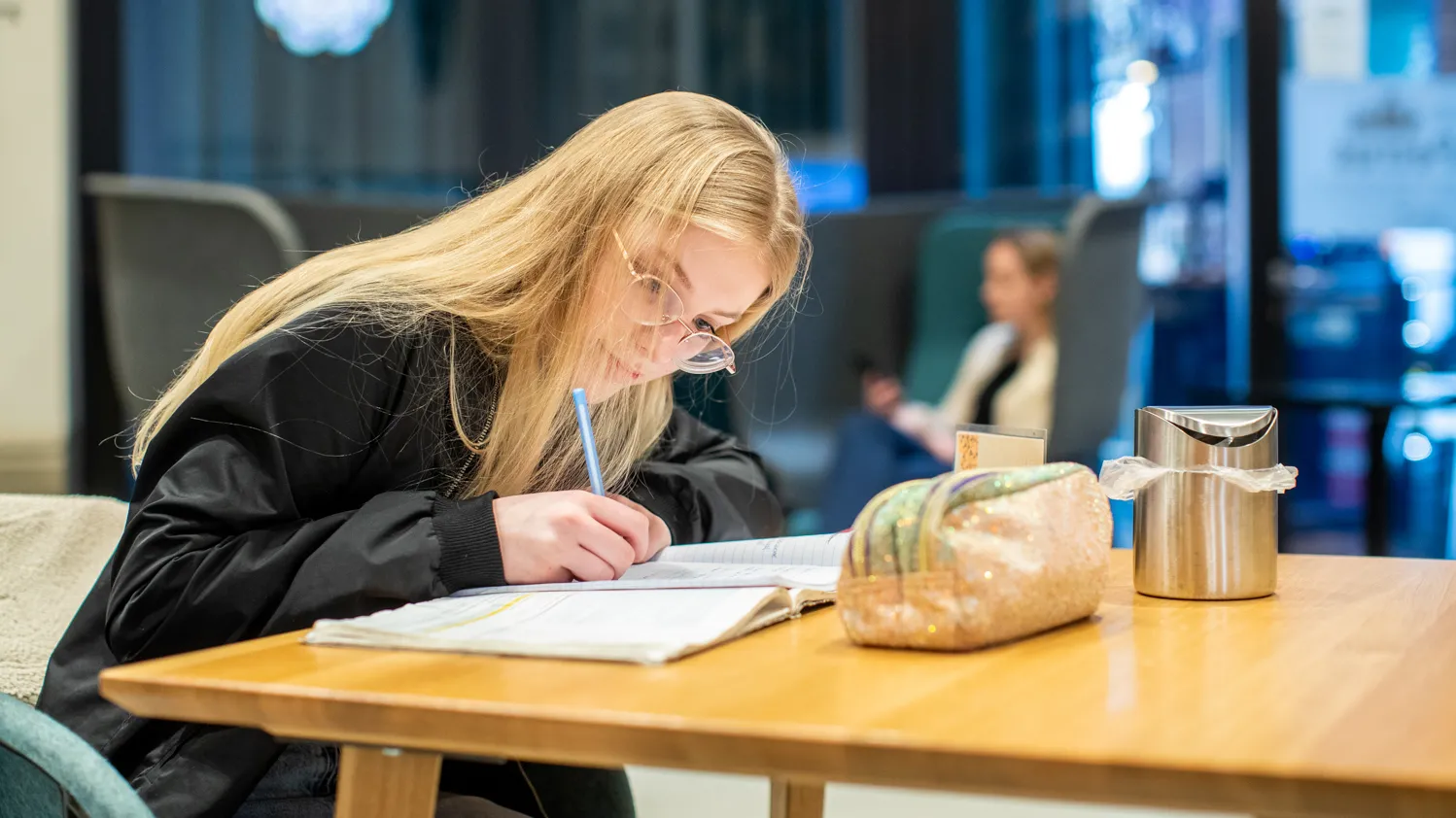 Jong meisje met lang blond haar zittend aan tafel met pen en schrift