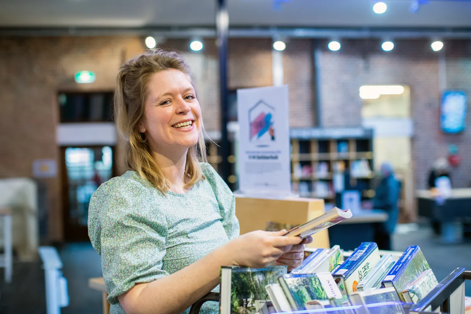 Vrouw met kar vol boeken in bibliotheek