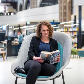 literatuur vrouw zittend in stoel leest boek in bibliotheek