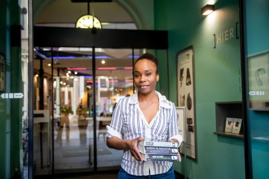 vrouw in ingang met stapel boeken