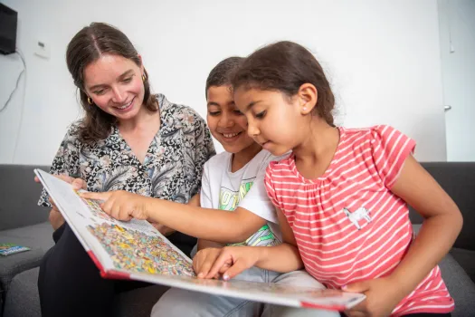 vrouw bekijkt boek met twee kinderen