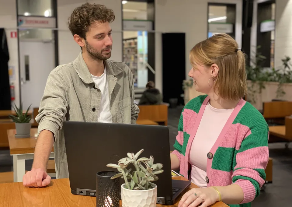 Jonge man en vrouw staand achter computer 