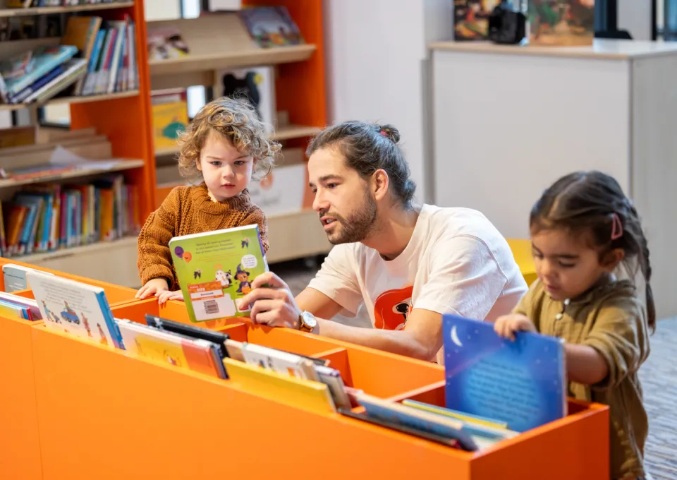 man en kinderen bij lage boekenkast