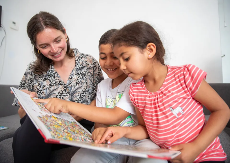 vrouw bekijkt boek met twee kinderen