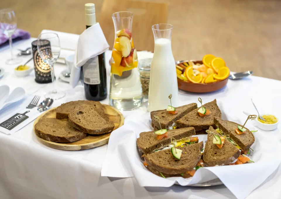 foto van gedekte lunchtafel met sandwiches fruit yoghurt melk water en wijn